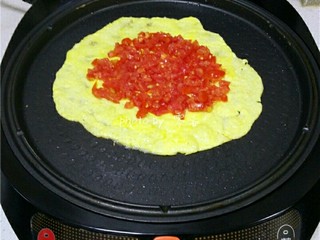 5、西红柿鸡蛋披萨,蛋液稍稍凝固后，在蛋饼中间铺上番茄丁；