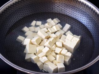 4、金针菇豆腐鱿鱼煲,锅中倒入适量的清水，把豆腐进行焯水，这样做出来的成品汤色清澈透亮。