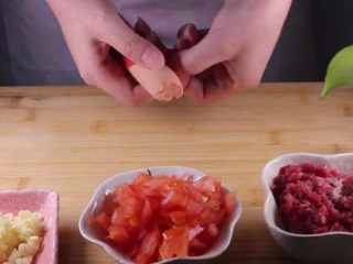 2、教你一个拌面的新吃法，口感爽滑劲道,首先将所有食材准备后，我们先将大蒜剁成蒜末、牛肉剁成牛肉糜、取半个番茄切成番茄丁、火腿肠壳后备用。