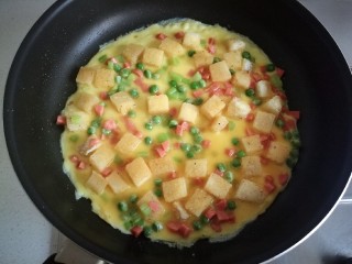 18、快手馒头伪披萨,筛进蛋液后，开中火，提起锅晃一晃，让蛋液再平铺的均匀点。