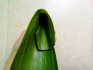 14、五花肉咸蛋黄腊肠粽,如图这样将粽叶一头折回来，形成漏斗状