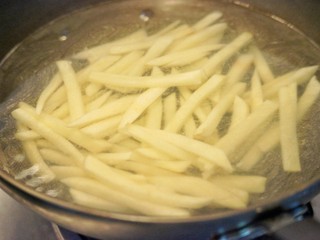 7、美式芝香薯条,大火烧开一锅水，下土豆条，煮8分钟左右。