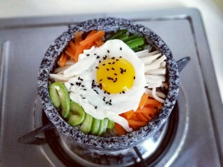 16、韩式石锅拌饭,将煎好的鸡蛋放入蔬菜上面，撒上少许熟黑芝麻，开小火大约3-5分钟，听到米饭发出滋拉滋拉的声音可以关火，锅底的米饭会有有一层锅巴，特别香。(一定要小火，一定要小火，一定要小火，重要的事情说三遍。）