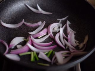 6、【韩剧美食做起来】の辣炒年糕,中小火,锅中倒入适量橄榄油,放入葱段和洋葱段,煸炒出香味