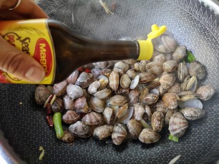 7、辣炒花蛤,大火翻炒至花蛤开始张口，加适量味极鲜酱油，继续大火翻炒。