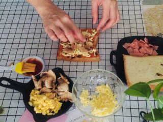 7、培根吐司比萨,将口菇一片片摆好在奶酪丝上，再把玉米粒均匀的撒在口菇上面。