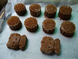 12、豆沙蛋黄月饼,如图按住模具，在烤纸上压实，推动模具使月饼生胚脱模