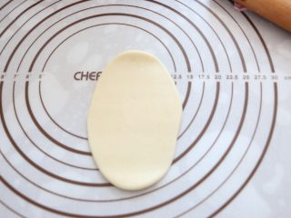 7、自制蛋黄酥,取松弛好的面团，压扁，擀成鸭舌状。