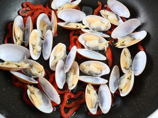 11、海鲜鲜意粉,红椒炒出香味后，加入花甲，大火翻炒2分钟左右。