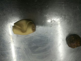 12、超级好吃的鲜肉月饼,把面团拿出来,中间按一下,两边往中间收,擀开,把肉馅放在中间,尽量擀大一点,然后收口,一定不要有漏的地方,否则烤的时候会漏油,把收口朝下放