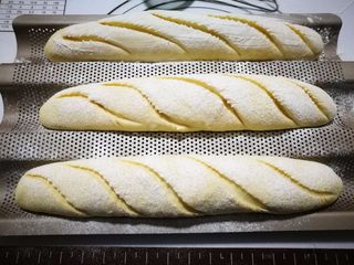 12、奶香法棍型面包,拿出面团，筛一层薄薄的面粉，然后用刀片斜着割五个口子。