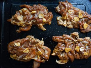 9、黯然销魂鸡腿肉,放烤盘蒜片均匀撒上