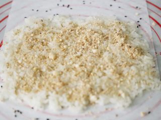 11、武汉小吃 糯米包油条,将打成粉的花生粉均匀的洒在铺好的糯米饭上。