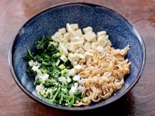 5、萝卜樱海鲜豆腐蒸饺,把焯过水的萝卜樱用刀切碎，放入一个容器里，再放入切碎的扇贝边和老豆腐，葱姜碎。