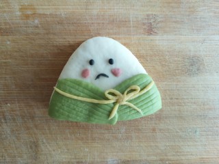 18、粽子饼夹&肉末梅干菜,取其他颜色面做成表情及配饰后用水贴在白色三角形上，粽子饼夹造型完成。