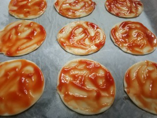 6、迷你披萨,用勺子将番茄酱抹匀