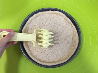 10、黄桃全麦披萨,把面团擀成比10寸的披萨盘大一点的圆面片，披萨盘内抹一层融化的黄油，然后放入擀好的面皮，用戳孔器把披萨皮压上孔