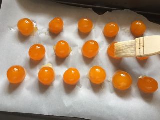 1、流心奶黄月饼,首先把所用到的咸蛋黄刷上一层米酒/玫瑰露酒，放入烤箱里，350华氏度（180摄氏度），烤8-10分钟。