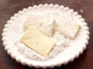 9、照烧北豆腐,盘子里放入适量的淀粉，把切片豆腐裹上一层薄薄的淀粉。