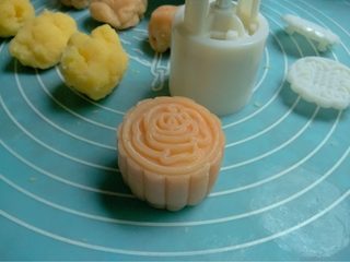 13、冰皮月饼,如图冰皮和馅儿各分25克一份，用冰皮包入馅儿揉圆，模具沾适量熟糯米粉再将多余的粉磕掉，将团放入模具内按压出自己喜爱的图案