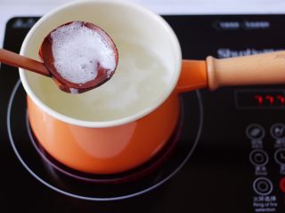 6、紫薯双米草莓粥,开锅以后,用勺子撇去浮末。