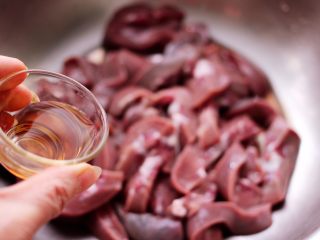 7、孜然香辣烤猪腰串,切好的猪腰放到一个大的容器里,先倒入料酒去除猪腰的腥气。