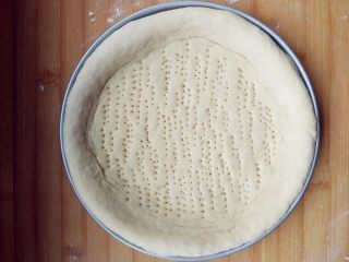 7、厚底鲜虾批萨,在披萨盘上涂少许黄油，将擀成厚片的饼皮放在披萨盘中，周围用手压出略高的边缘，用叉子扎一些孔（以免底部受热鼓起），入烤箱二次发酵30分钟左右