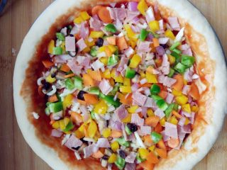 10、厚底鲜虾批萨,在涂了披萨酱的饼底洒少许奶酪碎，将混合蔬菜粒撒匀。可以撒一层料铺一层奶酪