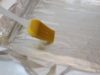 5、柠檬黑胡椒烤鸡翅,烤盘上铺好锡纸，要裁的大一些。用硅胶毛刷薄薄的刷一层油