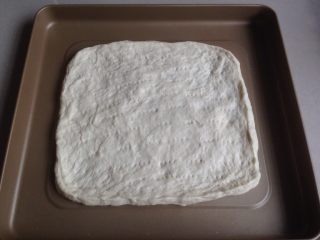 7、玉米培根披萨,排气后，松驰15分钟，再擀平，放在烤箱自带的不粘烤盘上，松驰15分，用叉子叉出小孔