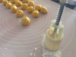11、椰蓉桃酥,桌面撒些面粉,50克规格的小月饼模先在面粉上按压一下粘些粉防粘