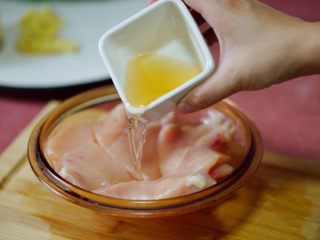 5、香辣秋葵手撕鸡,我是横片一刀,再对切一刀,变成4小片后,加料酒、生姜片腌制。此环节不要放盐,会影响肉质口味