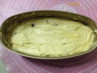 11、蔓越莓磅蛋糕,装入模具中，用刮刀抹平表面，端起模具在台面上轻磕几下让面糊均匀，稍微按压一下，使模具中的蛋糕糊呈现中间凹边缘高的状态