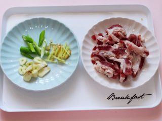 2、百吃不厌的双椒炒肉,用刀把蒜切成薄片，葱和姜切丝，五花肉切成条状备用。