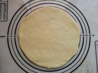 6、墨鱼热狗芝心披萨,把面团排气醒发15分钟后擀成约9寸大的饼皮。