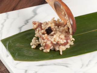 4、粽香排骨卷,洗净擦干的粽叶剪平头尾，在一头铺层拌好的糯米，摆上肋排，再铺层糯米