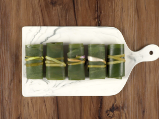 5、粽香排骨卷,将粽叶卷起，用绳子绑紧固定，依次包好全部