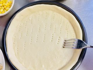 18、一次发酵——虾仁牛肉肠披萨,发酵好的饼皮取出,用叉子扎一些小洞,防止饼皮烘烤时鼓起。