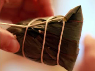 11、五花肉粽,咬住一头绳子，留一手掌的长度，从头开始绕，注意一定要拉紧；左后打结这样就完成啦