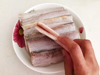 6、炸酥带鱼,鱼腹里面的黑膜要清除干净,加入料酒和精盐腌制30分钟