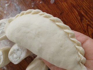 14、韭菜盒子,对折包成半圆，边上压实，拇指侧面向里内扣，捏上花边烙的时候不易开口。