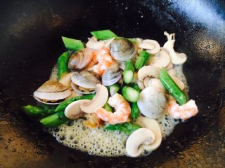 16、奶香浓郁 味道独特 简单易学 白汁海鲜意面,放入鲜虾仁、青蛤、芦笋，翻炒均匀。