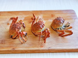 6、蒜泥螃蟹,取出煮好的蟹，放在砧板上，把下面的壳掰掉。