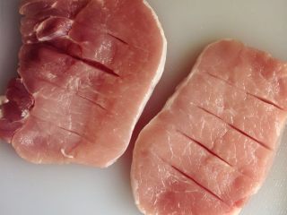 4、小芽早餐-日式炸猪排(烤箱版非油炸) ,将猪排用刀轻轻划出口子,每块猪排大概3-4刀,这样一是有利于后期盐、黑胡椒的吸收,二是用烤箱烤制的时候可以更加平整