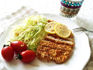 15、小芽早餐-日式炸猪排(烤箱版非油炸) ,切好卷心菜,能多细切多细哈,放入猪排、小番茄,再切两片薄薄的柠檬片提味,美味漂亮又健康的日式炸猪排就做好啦!