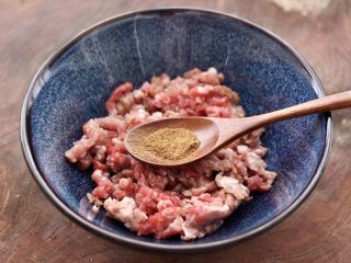 3、冬至美食～牛肉茼蒿饺子,把牛肉馅放入一个大一点的容器里，先倒入料酒和花椒粉。