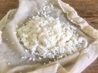 2、泰式芒果糯米饭【coconut sticky rice with mango】,沥干水分后 取一半的糯米放入蒸笼布上
