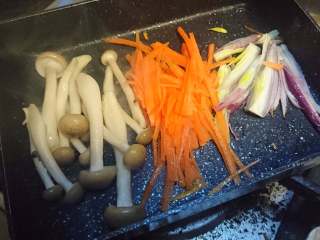 5、锡纸包烧鲑鱼,将洋葱丝，胡萝卜，真姬菇一起煎炒，用盐和生抽调味