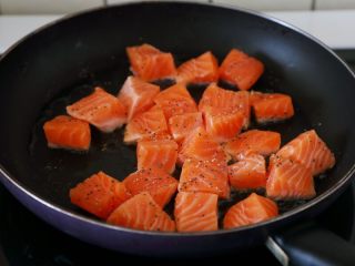 5、双椒土豆三文鱼,锅里多倒些油，油热将三文鱼块下锅，撒些黑胡椒碎和盐。