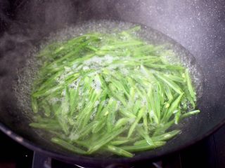 4、香肠辣爆芸豆丝,锅中倒入适量的清水煮沸后,放入芸豆进行焯水,看见芸豆丝变色变软时,捞出过冷水后沥干。